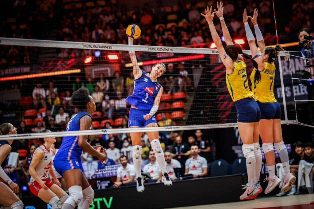 Héléna Cazaute, capitaine des bleues à attaque une balle. En face, deux Brésiliennes sautent pour contrer.